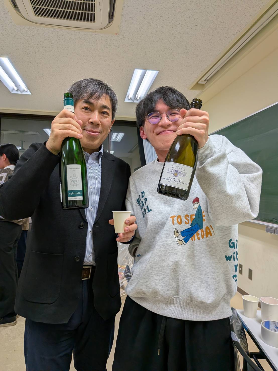 OBから頂いた日本酒を持ちご満悦の市川教授とドクターの学生