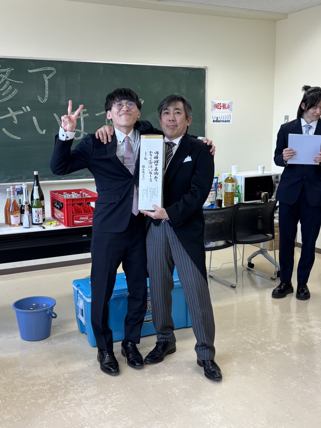 感謝のしるしとして、市川先生にお酒を贈呈する卒業生